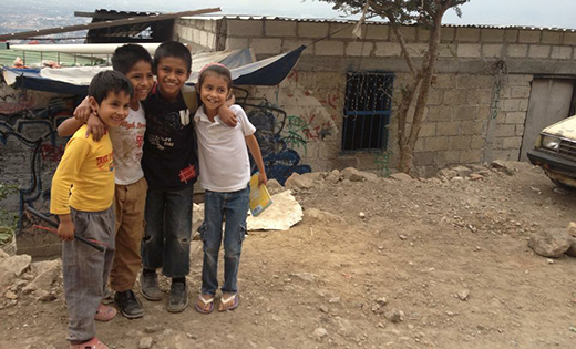 Four of the family’s six siblings stand in front of the house built by their father, with a view of the mountain in the background.