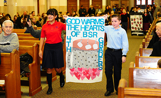 Nicholas Servini and Isabella Colone of Bishop Schad Regional School carry the fourth grade banner during a Mass at Sacred Heart Church, Vineland, on Jan. 29 to celebrate 95 years of Catholic education. Bottom, Msgr. Johm H. Burton, pastor, celebrates the Mass.