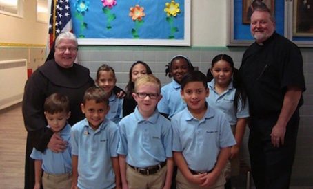 Sister Jerilyn Einstein FMIJ, principal at Guardian Angels School, is pictured with students and Father David Grover, pastor of Saint Clare of Assisi Parish, Swedesboro.