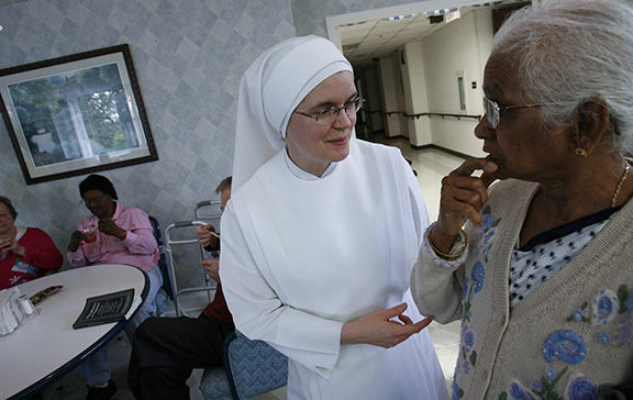 A member of the Little Sisters of the Poor assists a woman at the Little Sisters' Jeanne Jugan Residence in Washington, DC.
(CNS file photo)
