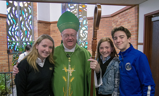 Bishop Dennis Sullivan has his arm on Katherine Kaderabek, who spoke about Catholic education during Mass for the opening of Catholic Schools Week at Saint Michael Church, Saint Clare of Assisi Parish, Gibbstown, on Jan. 28. Also pictured are Katherine’s sister, Caroline, a seventh grader at Guardian Angels Regional School, and her brother Michael, a sophomore at Paul VI High School, Haddonfield.