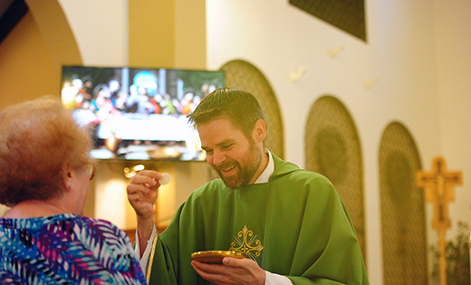 Father Christopher Klusman of the Archdiocese of Milwaukee, one of 11 Deaf priests in the United States, distributes Communion during Mass on Sept. 30 at Holy Saviour Church, Westmont.

Photo by Alan M. Dumoff