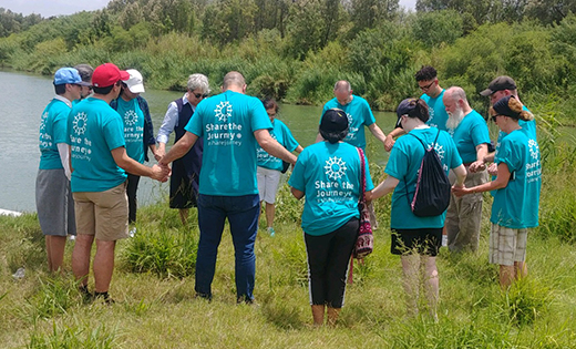 Thirteen missionary disciples from the Camden Diocese pray with Sister Norma Pimentel at the Rio Grande River. During each pilgrimage, Sister Norma (wearing sunglasses) spends time with every group, offering her insights as someone who has assisted over 100,000 migrants since 2014 through her role as executive director of Catholic Charities of the Rio Grande Valley.