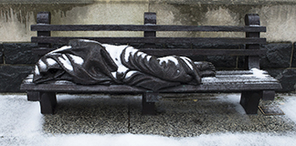 The "Homeless Jesus" sculpture by Timothy Schmalz is seen covered with snow outside Catholic Charities of the Washington Archdiocese Dec. 16, 2020. Later that day staff and volunteers distribute hot meals to the homeless outside the nearby Martin Luther King Jr. Memorial Library Dec. 16, 2020, amid the coronavirus pandemic. Enough food was made to feed 150 people. (CNS photo/Tyler Orsburn)