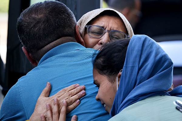 Afghan refugees at Dulles International Airport in Dulles, Va., embrace family members Sept. 2, 2021, before boarding buses that will take them to a processing center. (CNS photo/Evelyn Hockstein, Reuters)