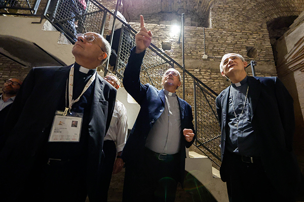 Cardinal Matteo Zuppi, president of the Italian bishops conference, and Archbishop Bruno Forte of Chieti-Vasto, Italy, walk through Rome's Catacombs of St. Sebastian as Msgr. Pasquale Iacobone, president of the Pontifical Commission for Sacred Archeology, gives them a tour as part of a pilgrimage by participants in the assembly of the Synod of Bishops, Oct. 12, 2023. (CNS photo/Lola Gomez)