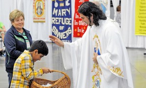 Father Ariel Hernandez, pastor of Our Lady of the Blessed Sacrament in Newfield, blesses Braden Deshai as he brings gifts to the altar during Mass.