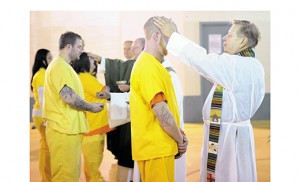 Father Dennis Bajkowski blesses an inmate of the Camden County Correctional Facility, Camden, on Jan. 15. In the background Bishop Dennis Sullivan, who celebrated Mass in the facility with Father Bajkowski and other clergy, blesses another inmate. Photo by Alan M. Dumoff 