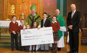 Bishop Dennis Sullivan accepts a check for $158,000 for the South Jersey Scholarship Fund Jan. 28 at St. Teresa Church, Runnemede. Also pictured are Father Robert Hughes, Vicar General; George Lynn, South Jersey Scholarship Fund, and the Moleski children (from left: Michael, John Paul, Joseph, Mary Grace, Monica and Anna). The Scholarship Fund was established to provide financial assistance to educate needy children in schools operated by the Diocese of Camden. It operates as a separately incorporated organization with its own board of trustees. The check represents proceeds from the Celtic Twilight Christmas Concert held Dec. 6, 2014, at the TD Bank Arts Centre, Sewell. Above, children of St. Teresa School at Mass. Photos by James A. McBride 