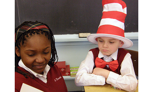 Sixth grader Suzy Ndandji reads to second grader Harry Moore on March 2, the birthday of Dr. Seuss, at St. Teresa School, Runnemede. Below, Eddie Davis of Literock 96.9 WFPG begins his Read Across South Jersey tour by reading “The Cat in the Hat” at St. Vincent de Paul Regional School, Mays Landing.