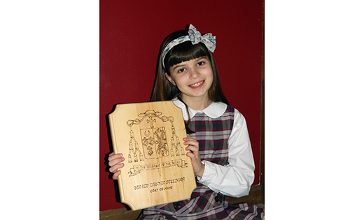 Rachel Haverly holds a plaque she made with Bishop Dennis Sullivan’s coat of arms. She explained its meaning to her fourth grade class at St. Margaret Regional School in Woodbury Heights. She also shared with her classmates her email interview with him, which covered his family and spiritual life, the languages he speaks and sports.