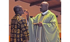 Photo by Alan M. Dumoff On July 12, the African-American and Caribbean communities of South Jersey and Philadelphia came together for worship and fellowship at St. Charles Borromeo Parish in Sicklerville, as part of their monthly gathering. Above, Reggie Wilburn receives Communion from Father Michael Ezeatu. 