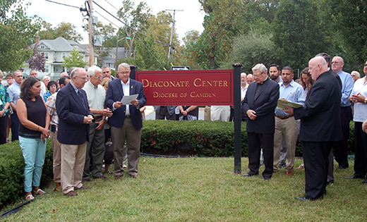 Father Robert Hughes, Vicar General for the Diocese of Camden, blesses the new Diaconate Center in Vineland on Sept. 12, its first day of formation sessions for men studying for the permanent diaconate. The dedication followed an open house of the new facility, the site of the former Sacred Heart High School. It includes classrooms, a library and a chapel. The Parish of Christ, the Good Shepherd, collaborated with the diocese on opening the new center. Next to Father Hughes is Msgr. John Burton, pastor of Christ, the Good Shepherd. Standing at left is Deacon Leo McBlain, director of personnel for the permanent diaconate. Not pictured is Deacon Michael J. Carter, director of formation for the permanent diaconate.

Photo by James A. McBride