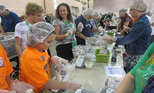 Christy Wimberg (third from left) of St. Gianna Beretta Molla Parish, Northfield, helps pack meals that will be delivered to West African nation Burkina Faso. The Catholic Relief Services project took place during the World Meeting of Families at the Pennsylvania Convention Center in Philadelphia last week.

Photos by Joanna Gardner

Tyler Wimberg, below, and his brother Connor work the line with their
mother.