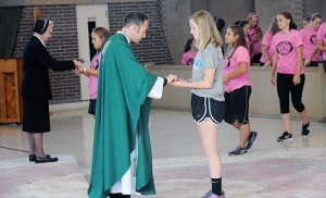 Abbey Lord, Paul VI senior and captain of the school’s varsity field hockey team, receives Communion from Father John Rossi during the memorial Mass for Ann Marie Lynch at St. Vincent Pallotti Church, Haddon Township, on Oct. 23. Photo by Alan M. Dumoff