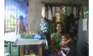 Mary Jane Castil and her youngest child, three months old, are pictured in the store attached to her home in Tolosa. She and her family lost their home and business when Typhoon Haiyan hit two years ago. With the help of Catholic Relief Services Recovery Program, her family has been able to rebuild their home and restart — and even expand — their business. Photo by Joanna Gardner