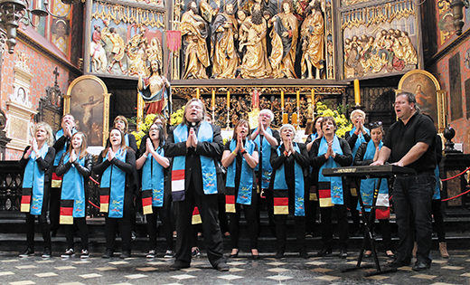 Father Krzysztof Wtorek with his international Gospel-Rock group sing in front of the altar of Wita Stwosza (Saint Mary’s altar) at St. Mary’s Basilica in Krakow, Poland last year. The altar is the largest Gothic altarpiece in the world, and a national treasure in Poland. Father Wtorek, parochial vicar at Holy Trinity Parish in Margate, and his group will perform at World Youth Day in July.

Photo by Ekkehard Heim