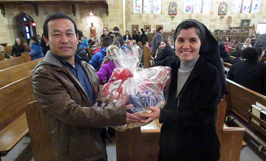 Sister Rosa Maria Ojeda, principal of Saint Peter School, Merchantville, presents Catholic Charities’ Refugee case manager aide Hting Mangshang with a ceremonial basket of the donated items.