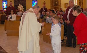 Making his first Communion April 17, Timothy Chaykin receives the host from Father Mark Cavagnaro, pastor of Our Lady of Hope Parish, Blackwood. Three other students in the parish’s Saint Bart’s Program, a religious education class for children with special needs, also received the sacrament that day. Pictured below with Father Cavagnaro are  teachers Jim and Kim Forte and Vincent Tenuto, Gavin Jefferies, Timothy and Lucas DeCosta. Photos by James A. McBride