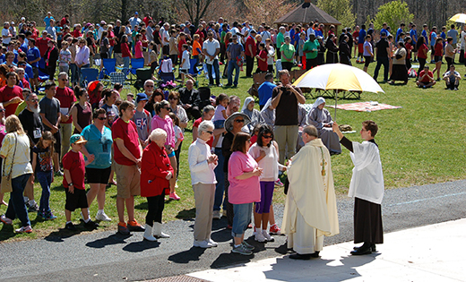 Bishop Dennis Sullivan distributes Communion to the faithful on the lawn of Washington Lake Park April 17 during the liturgy for the iRace4Vocations. Pictured with the bishop is seminarian Matthew Pluta. After the 1 p.m. Mass, participants engaged in a 5K run/1.3 mile walk.

Photo by James A. McBride
