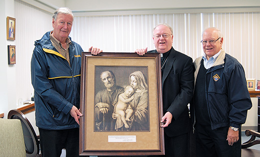 Representing the New Jersey State Knights of Columbus, Reggie Beckett, left, Vice Supreme Master of the Fourth Degree, and Andy Lipenta, Immediate Past State Deputy, present a painting of the Holy Family by 18th century artist Giovanni Balestra to Bishop Dennis Sullivan in the Camden Diocesan Center on May 10.

Photo by James A. McBride