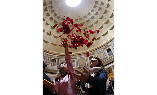 Women toss rose petals after Rome firefighters dropped the petals from the oculus of the Pantheon at the conclusion of Pentecost Mass May 15. The rose petals symbolize the tongues of fire that came upon the apostles at Pentecost. (CNS photo/Paul Haring)