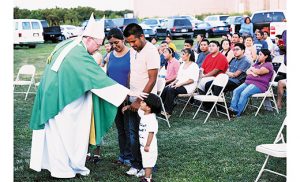 Bishop Dennis Sullivan blesses a child during the offertory at the farm Mass he celebrated Aug. 13 at Larchmont Farms in Elmer.