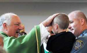 Father John O’Leary, pastor, blesses a child during the Blue Mass, honoring first responders and all law enforcement personnel, at Our Lady of Angels Church, Cape May Court House, on Sept. 11. Photo by Alan M. Dumoff, ccdphotolibrary.smugmug.com