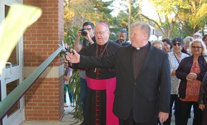 With a ribbon cutting, Bishop Dennis Sullivan and Father Thomas Newton, pastor, officially open the new parish center at Cherry Hill’s Catholic Community of Christ our Light Oct. 16. The new multi-purpose facility includes a gym, auditorium, conference rooms and office space. Photo by James A. McBride