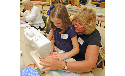 Monica Arleth works with Caleigh Paskalides to make a dress at the Make a Difference Day service event Oct. 22 at Saint Joseph Parish, Somers Point. Some 60 volunteers made dresses that will be sent to girls in impoverished areas through Dress A Girl Around the World. Right, a girl wears a dress she received through the organization.

Photo by Alan M. Dumoff