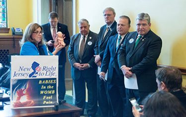 Marie Tasy, executive director of New Jersey Right to Life, holds a plastic baby doll representing what an infant in the womb looks like at 20 weeks gestation as lawmakers in Trenton look on.

Joe Moore photo