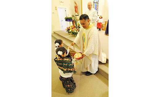 Father Armando Rodriguez Montoya, part-time parochial vicar for Hispanic Ministry, blesses an image of Our Lady of Guadalupe at the start of a procession at Our Lady of Perpetual Help Parish, Galloway. The procession was followed by Mass at Saint Nicholas Church, Egg Harbor City. Below, Father Montoya accepts offertory gifts during Mass.
Photo by Alan M. Dumoff