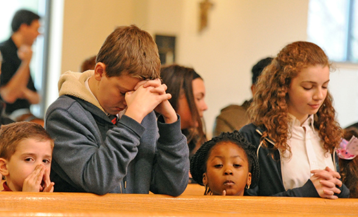 Students of Saint John Paul II School, Stratford, pray during a school Mass.
Photo by Alan M. Dumoff