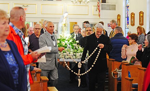 Parishioners process into church carrying a statue of Mary.
Photo by Alan M. Dumoff