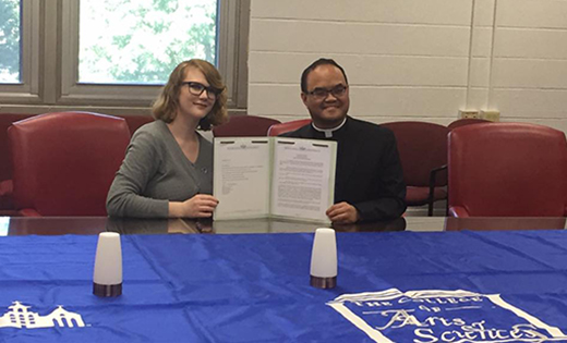 Saint Joseph High School, Hammonton, and Seton Hall University signed a dual-credit partnership on Sept. 25. An initiative of Saint Joseph's Pathway to College Program, students are able to earn college credits while still in high school. The partnership with Seton Hall will potentially save Saint Joseph High School students thousands of dollars in college tuition and place them on an advanced track entering college. Above, Father Allain B. Caparas, president/principal of Saint Joseph High School, signs a partnership agreement with Francesca Phillippy, assistant director of Project Acceleration at Seton Hall University.