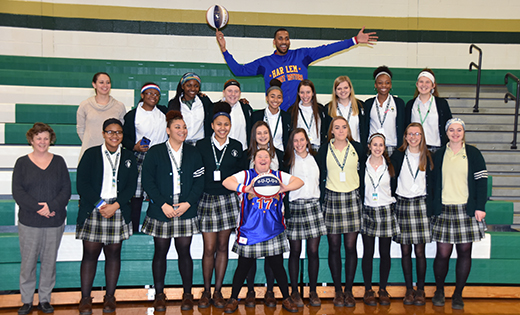 The Harlem Globetrotters’ Zeus McClurkin and the Camden Catholic High School basketball team stand behind senior Kate Spadaro. McClurkin visted the Cherry Hill school Feb. 22, a week after Kate, who has Down syndrome, commanded attention on the court during a Senior Night game against Lenape.