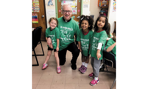 Father Vincent Guest, pastor of Our Lady of Guadalupe Parish, Lindenwold, poses for a photo with students of Saint John Paul II Regional School, Stratford, on May 14, its annual day of service.