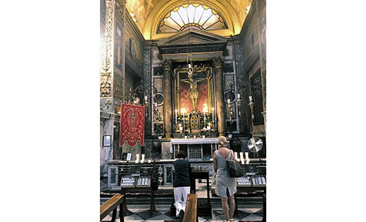 Women pray before the crucifix in the Church of Pope Saint Marcello on Via del Corso in Rome.
