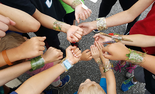 Students wearing their handmade bracelets put their hands together at Saint Michael the Archangel Regional School, Clayton, summer camp.