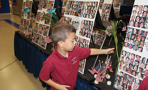 First grader Landon Buscemi places a flower at a display at Saint Michael the Archangel School, Clayton, memorializing the victims of the 9/11 terrorist attacks 17 years ago. Nearly 3,000 people died in the 2001 attacks on New York City, Shanksville, Pa., and the Pentagon. At Saint Michael, each grade level watched a slide show and observed moments of silence.