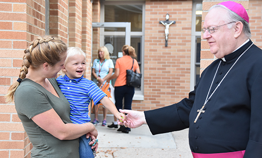Bishop Dennis Sullivan greets Jase and his mother, Jamie Dillich, after dropping Jase’s three older brothers off at Our Lady of Mount Carmel Regional School, Berlin, on Sept. 6.

Photo by James A. McBride