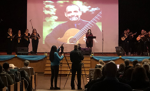 Damaris Thillet, associate director of the Diocese of Camden’s Office of Worship, performs a concert at Philadelphia’s Aspira Educational Campus on Dec. 16 in memory of her late husband, Diego, whose image is on the screen behind her.