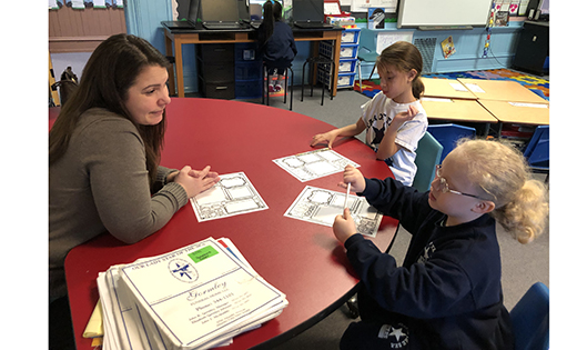 First grade teacher Mimi Lovallo works with two students while their classmates read silently, study spelling words in pairs, or work on the computer at Our Lady Star of the Sea, Atlantic City.