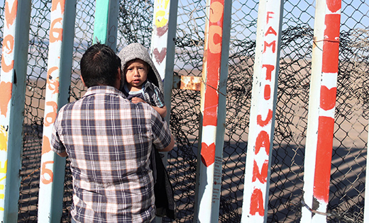 A man in Tijuana, Mexico, holds his son Jan. 3 next to a section of the wall separating Mexico and the United States.

(CNS photo/Mohammed Salem, Reuters)