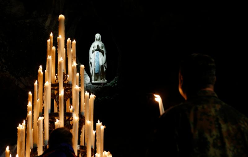 Candles are seen around a statue of Mary in the grotto at the Shrine of Our Lady of Lourdes in France in this file photo. The shrine will hold a worldwide virtual pilgrimage July 16, the anniversary of the last apparition of Mary. (CNS photo/Paul Haring) See COVID-VIRTUAL-LOURDES July 10, 2020.