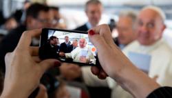 A journalist takes a cell phone photo of Pope Francis Jan. 23, 2019, aboard his flight from Rome to Panama for World Youth Day. (CNS photo/Vatican Media) See POPE-PANAMA-JAPAN Jan. 23, 2019.