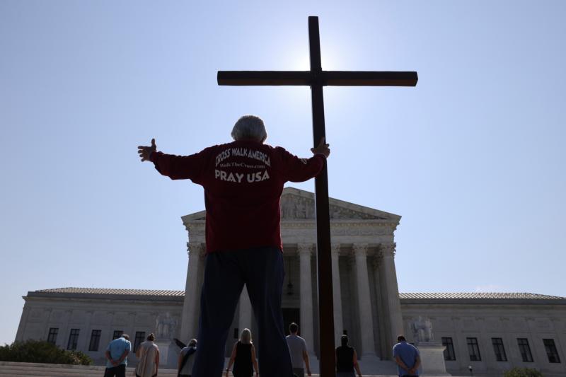 A demonstrator in Washington holds a large cross outside the U.S. Supreme Court  July 8, 2020. (CNS photo/Jonathan Ernst, Reuters) See SCOTUS-CONTRACEPTIVES July 8, 2020.