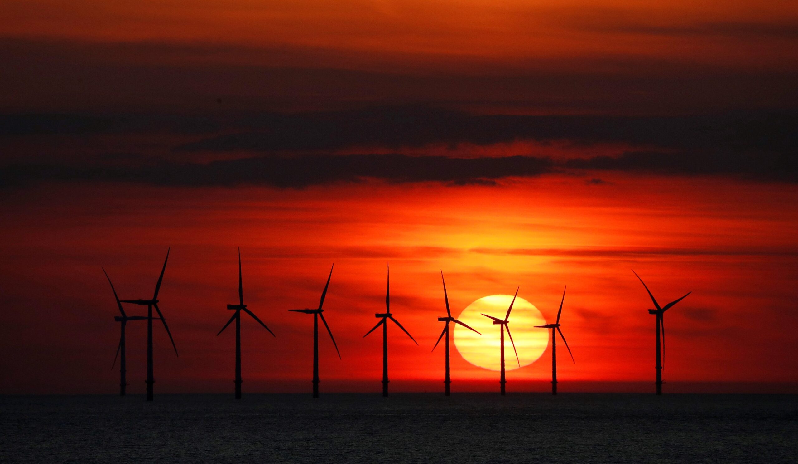 The sun sets behind a wind turbine farm near New Brighton, England, in this file photo. (CNS photo/Phil Noble, Reuters)