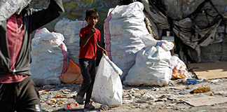 Iraqi boys collect recyclable garbage at a dump in Najaf, Iraq, Oct. 23, 2020. In a Nov. 30 video message, Pope Francis said that social justice for all men and women cannot be achieved if most of the world's wealth is controlled by a small percentage while the rights of others to a dignified life are disregarded. (CNS photo/Alaa Al-Marjani)