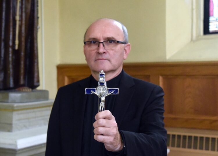 Father Vincent Lampert, exorcist for the Archdiocese of Indianapolis, holds a crucifix Dec. 2, 2020, in St. Michael Church in Brookville, Ind. He is the author of "Exorcism: The Battle Against Satan and His Demons" and is pastor at St. Michael and at St. Peter Church in Franklin County, Ind. (CNS photo/Sean Gallagher, The Criterion)